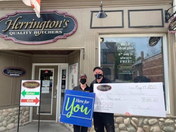 Two individuals from Herrington's Quality Butchers holding up a Here for You campaign poster and a cheque for the Port Perry Hospital Foundation's Here for You campaign