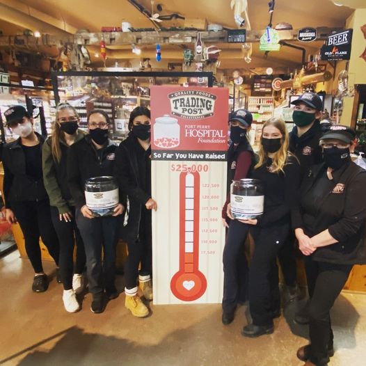 Trading Post Quality Foods staff members with a fundraising goal thermometer of 25,000 dollars inside the Trading Post