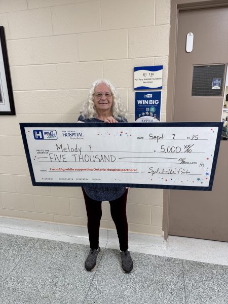 Melody holding a cheque presentation sign.
